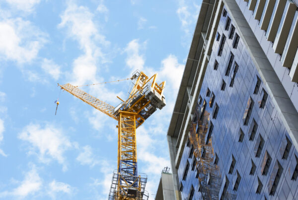 Modern apartment building under construction in Victoria with engineers inspecting structural works, representing latent defect insurance oversight